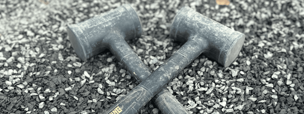 Two Estwing deadblow hammers sitting in gravel